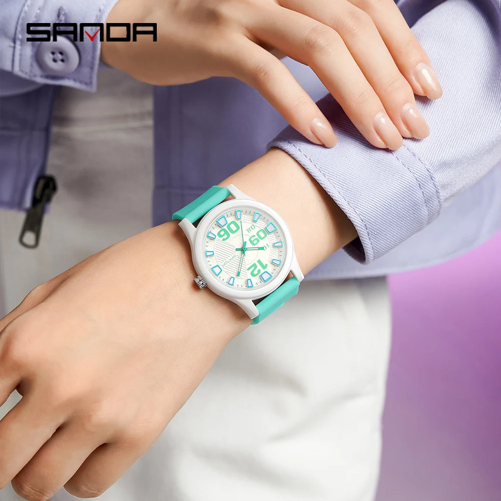A close-up of a white classic quartz fashion watch with a teal silicone strap worn on a wrist.
