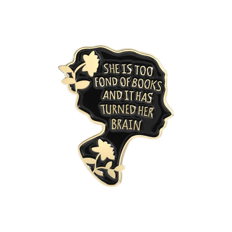 A black enamel lapel pin shaped like a brain with a floral design and text reading She is too fond of books and it has turned