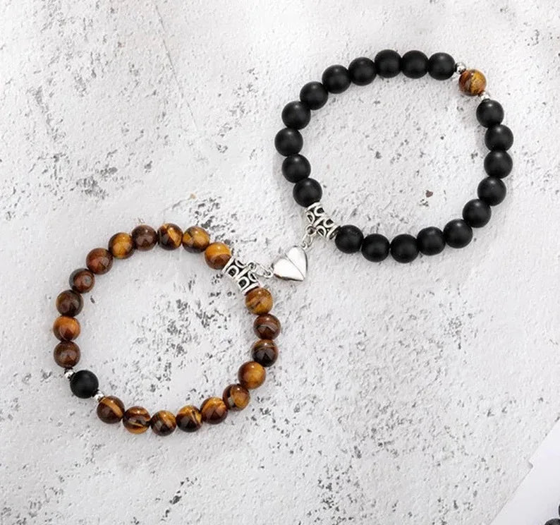 A pair of natural stone couple bracelets featuring dark black and amber beads with silver heart charms.