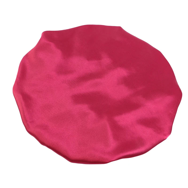 A vibrant magenta satin sleep bonnet with an elastic band.