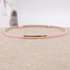 Pinkes Leder-Slim-Gurt mit goldener Schnalle auf beigem Stoff