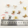 A collection of ten small, gold-colored metal butterfly hair clips displayed next to a ruler.