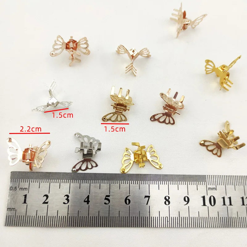 A collection of ten small, gold-colored metal butterfly hair clips displayed next to a ruler.