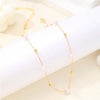 Collier délicat en or avec de petits charms de perles sur fond blanc.