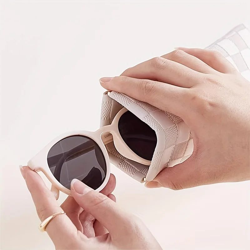 Eine Hand öffnet eine beige Lederhülle für eine Sonnenbrille.