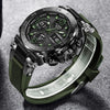 A luxury men's chronograph dive watch with a dark green bezel and black strap is shown on a gray background.
