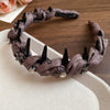 A dark gray resin wave toothed headband adorned with silver crystals and black spikes.