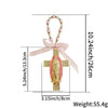 A pink and gold Catholic charm featuring a cross with a figure of the Virgin Mary and a pink ribbon.