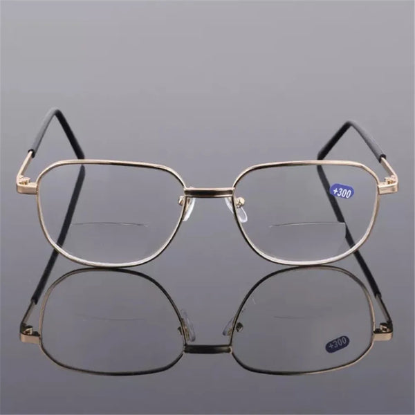 A pair of thin, gold-rimmed bifocal reading glasses resting on a reflective surface.