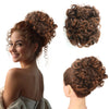 A woman shows off a brown synthetic curly chignon hairstyle, featuring loose curls and a messy bun look.