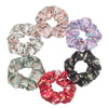 Un set de seis gomas de tela con estampado floral de satén en varios colores pastel y oscuros, dispuestos en círculo.