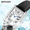 Eine silberne Uhr mit blauem Zifferblatt und Lederarmband spritzt im Wasser.