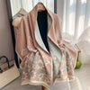 A soft pink and beige plaid cashmere feel scarf and shawl wrap draped on a hanger.