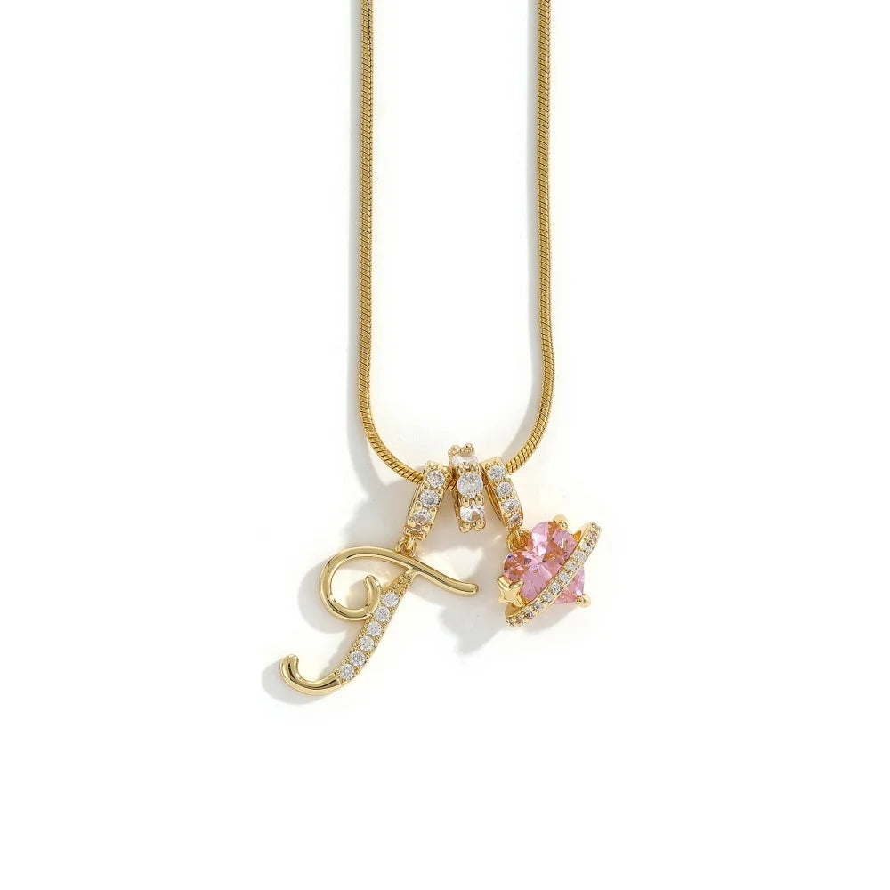 A gold letter M pendant necklace featuring sparkling stones and a pink flower charm.