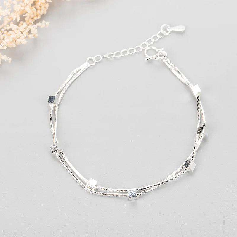 Sterling silver double heart charm bracelet with a delicate chain and small charms