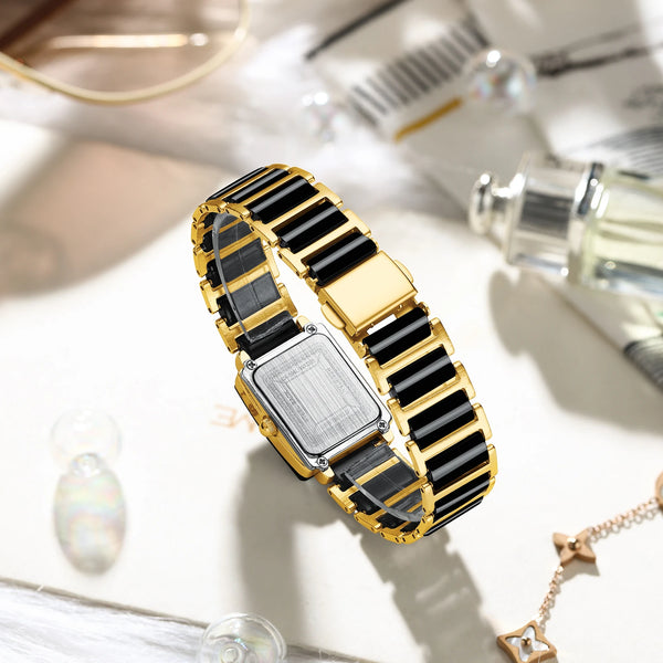 A gold and black ceramic fashion wristwatch is displayed on a white surface with other accessories.