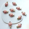 A set of ten pink ladybug hair clips with gold-toned findings arranged on a white surface.