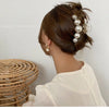 A woman shows off a hairstyle with simulated pearl hair claws and earrings.
