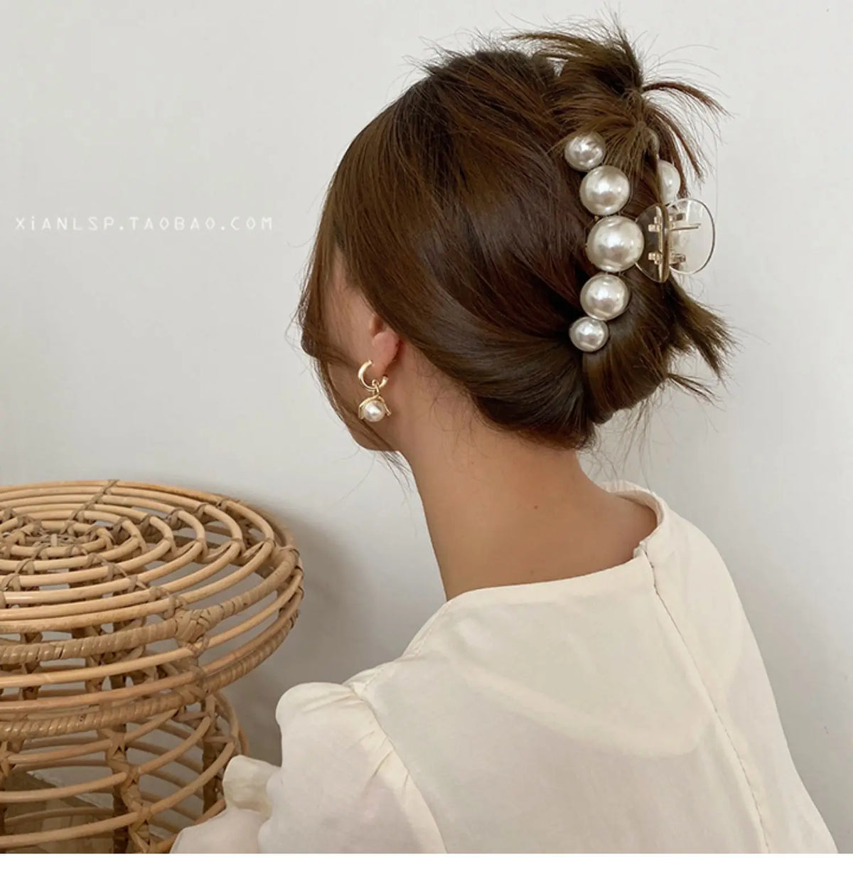 A woman shows off a hairstyle with simulated pearl hair claws and earrings.