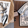 A black and white floral print silk scarf tied in a bow displayed on a tan blazer.