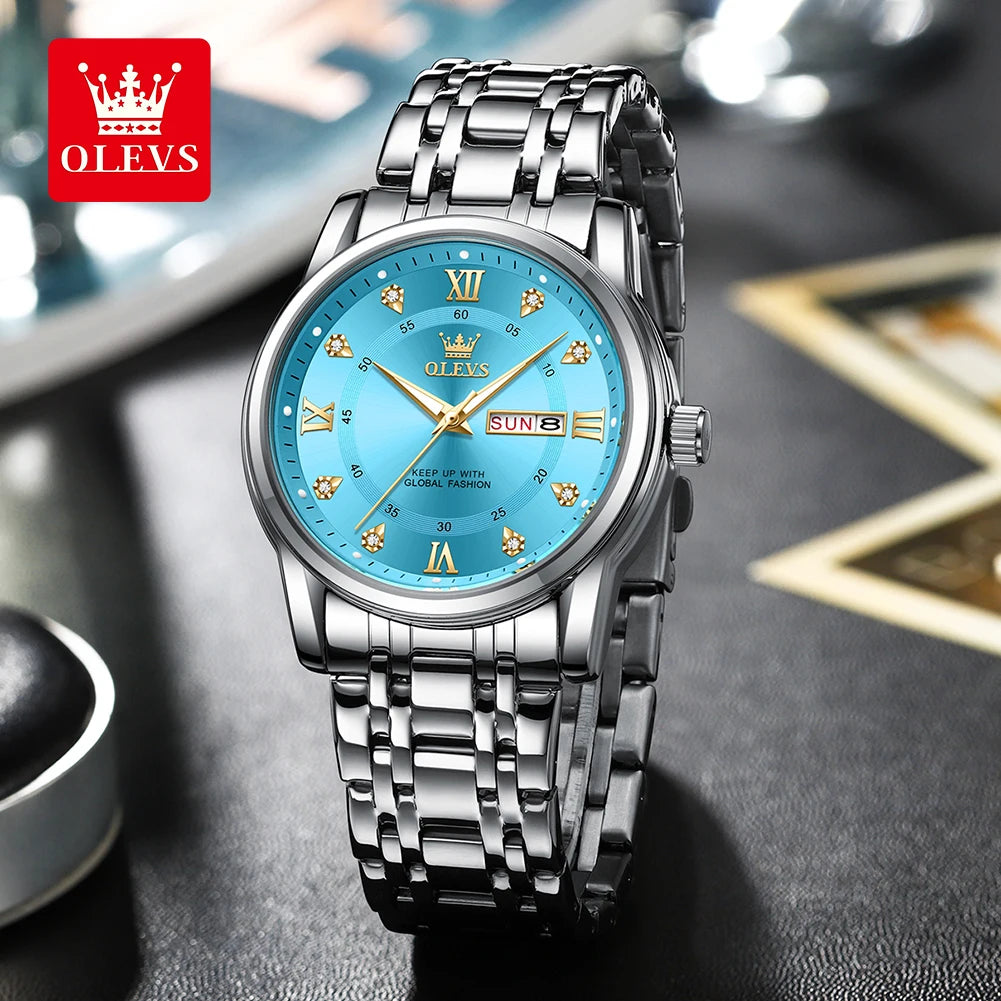 A silver stainless steel watch with a blue dial, Roman numerals, and luminous hands on a dark surface.