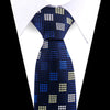 A dark blue silk necktie with a repeating white and gold floral pattern worn against a white shirt.