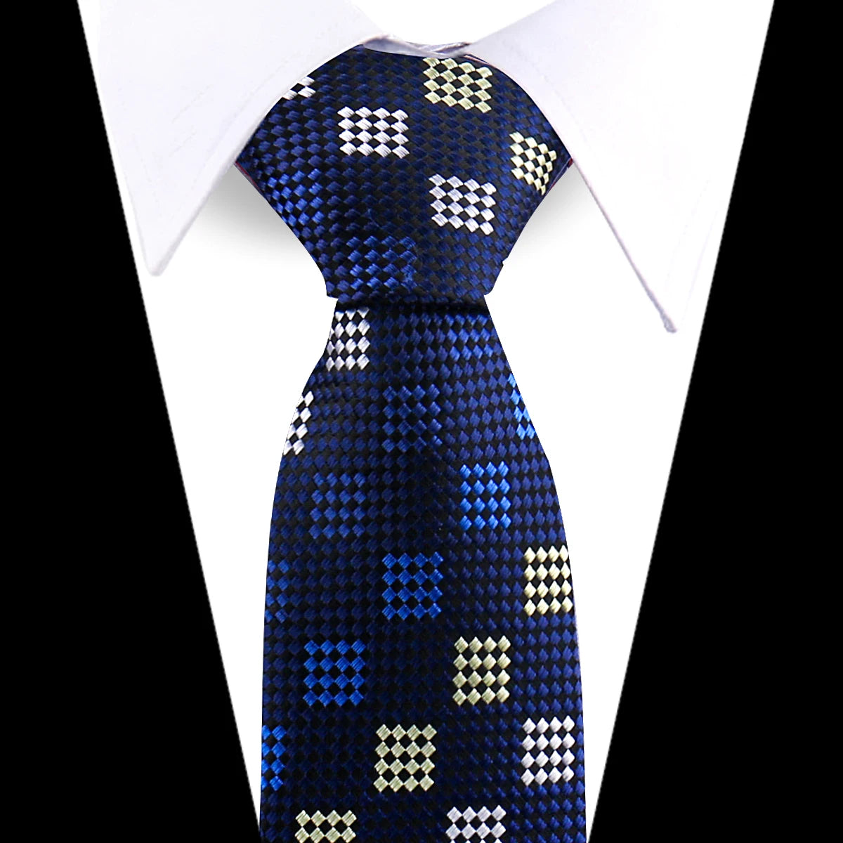 A dark blue silk necktie with a repeating white and gold floral pattern worn against a white shirt.