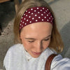 Une femme portant un bandeau de sport à pois marron et un sweat-shirt gris clair.