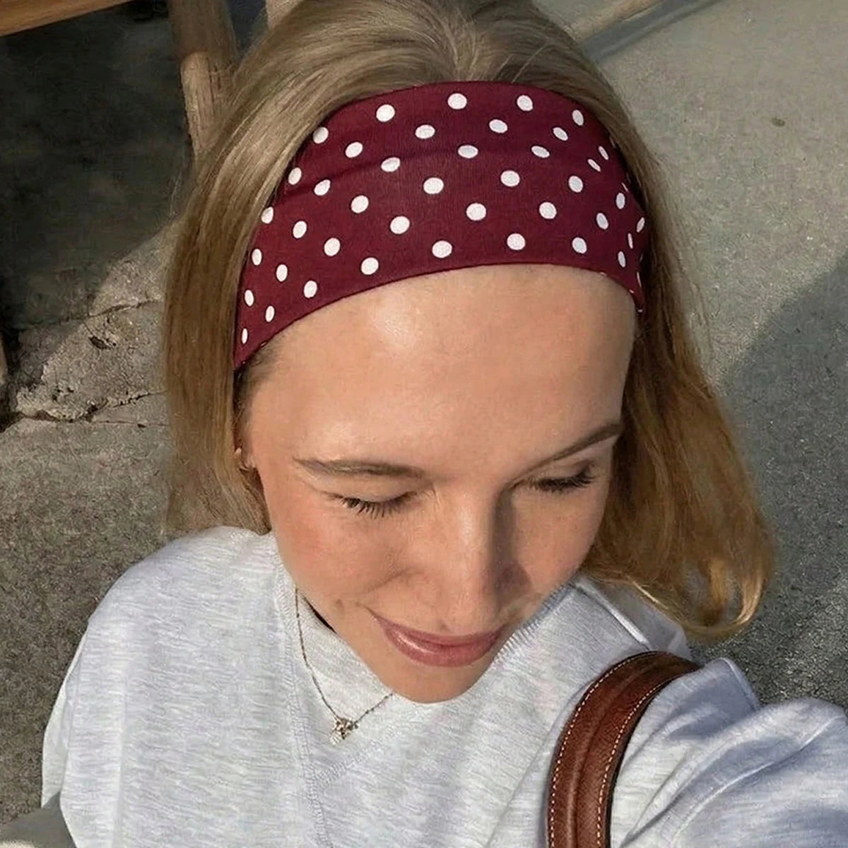 Une femme portant un bandeau de sport à pois marron et un sweat-shirt gris clair.