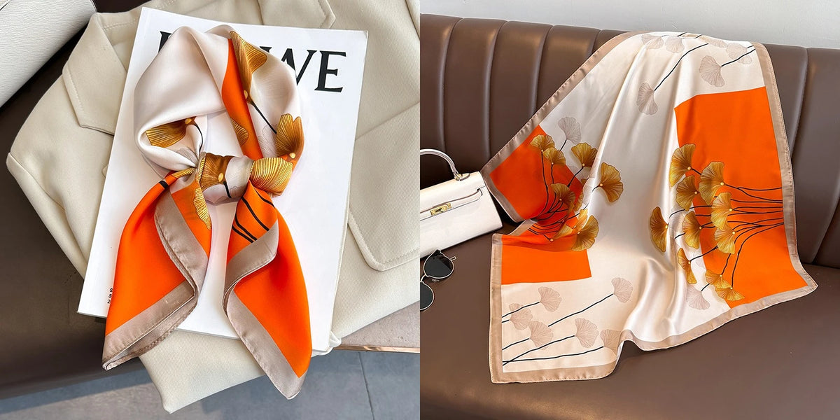 A peach and orange floral print silk scarf draped on a white card against a beige fabric background.