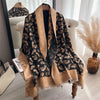 A black and gold patterned cashmere scarf draped over a white chair.