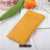 A yellow premium PU leather storage bag resting on a white surface next to a laptop and an orange flower.