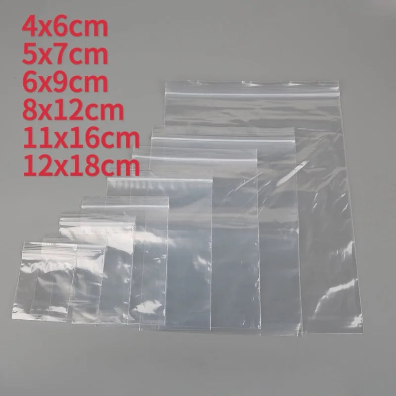 A collection of clear reusable ziplock storage bags in various sizes and dimensions stacked together.