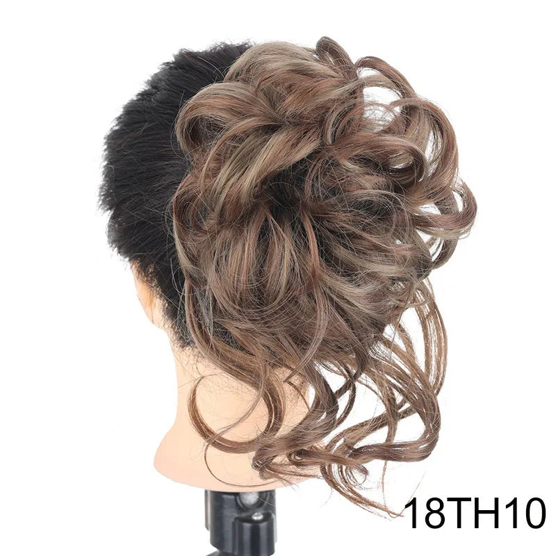A close-up of messy brown synthetic hair styled in an elegant updo or bun on a mannequin head.