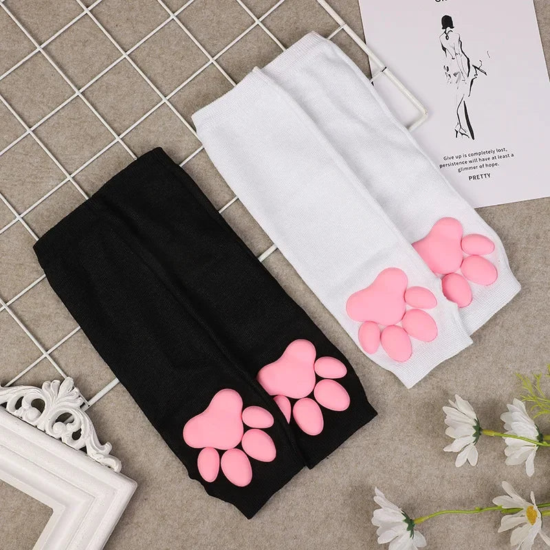 Black arm sleeves with pink cat paw designs displayed on a beige surface.