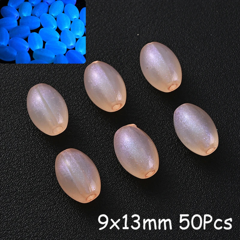 A collection of translucent pink acrylic beads and blue glow-in-the-dark beads are displayed on a black surface.