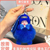A bright blue fluffy cartoon plush doll with a blue hat and bow is being held by a hand.