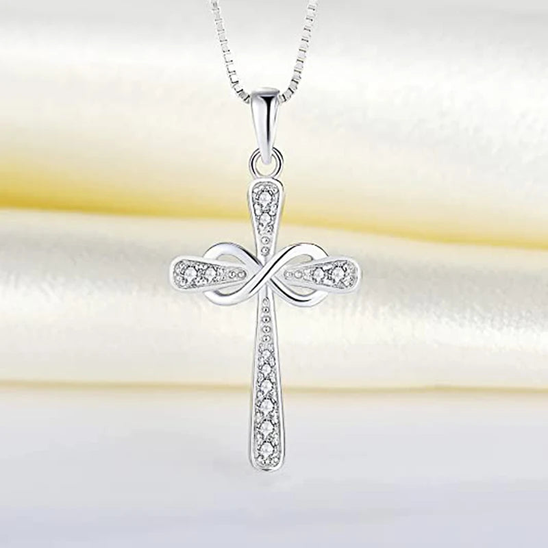 A silver cross pendant necklace with a detailed design and sparkling stones displayed on a white background.
