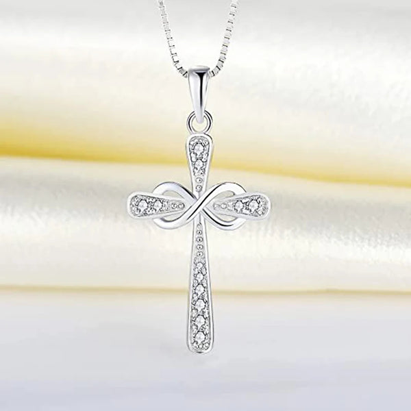 A silver cross pendant necklace with a detailed design and sparkling stones displayed on a white background.