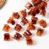 A collection of small, amber-colored adjustable hair claw clips arranged in a clear plastic container.