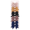 Un set de pinzas para el cabello con forma de lazo infantiles de colores sólidos en rosa, dorado, negro y gris.