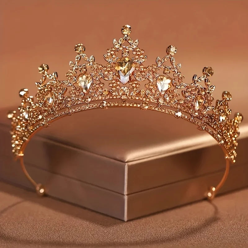 Diadema de cristal barroco dorado con piedras brillantes sobre una caja cuadrada.