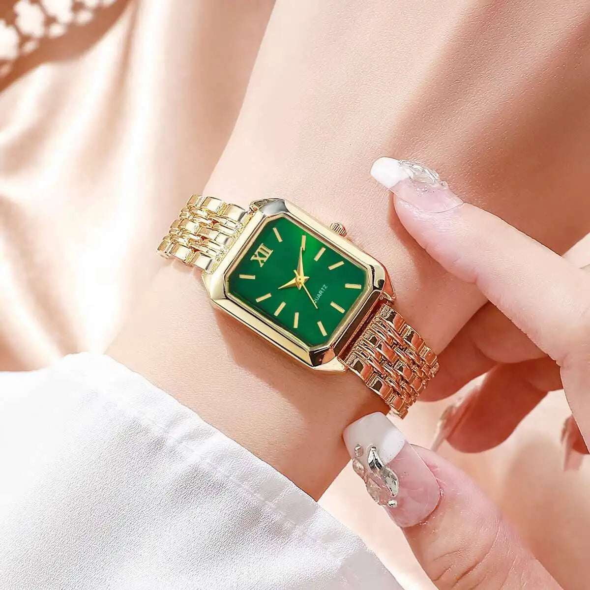 Reloj analógico de cuarzo dorado con esfera verde y eslabones dorados en la muñeca de una persona.