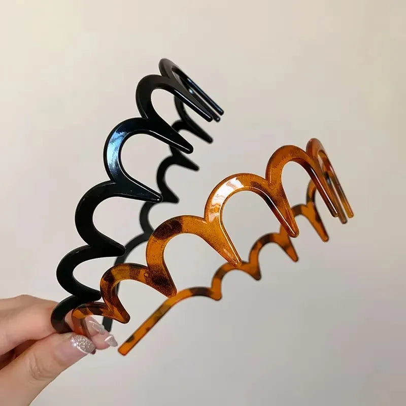 A close-up of a brown resin wave toothed headband for women, featuring black and amber colored teeth.