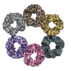 Un set de seis gomas para el pelo de satén con estampado floral en varios patrones de leopardo y florales, dispuestos en círc