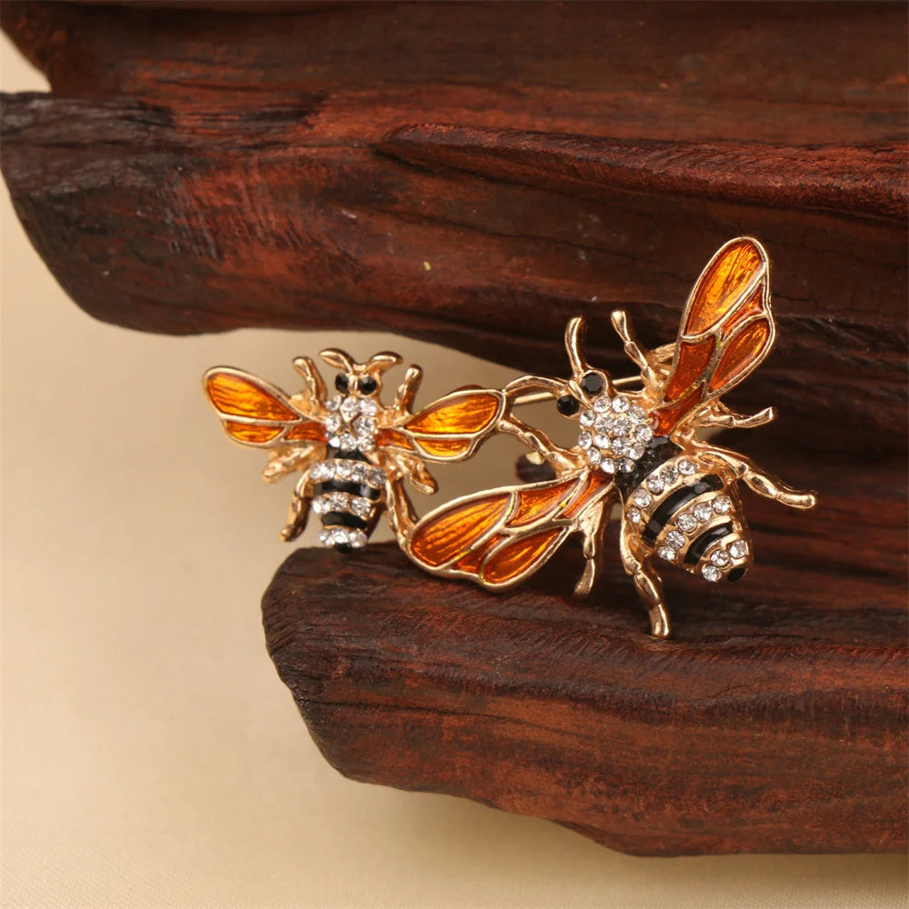 Broche ton or avec des motifs de abeille et d'insectes baroques sur une surface en bois sombre.