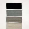 A set of four knitted hair bands in black, gray, taupe, and beige stacked vertically.