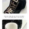 A close-up of a black embroidered letter baseball cap with gold lettering on the front.