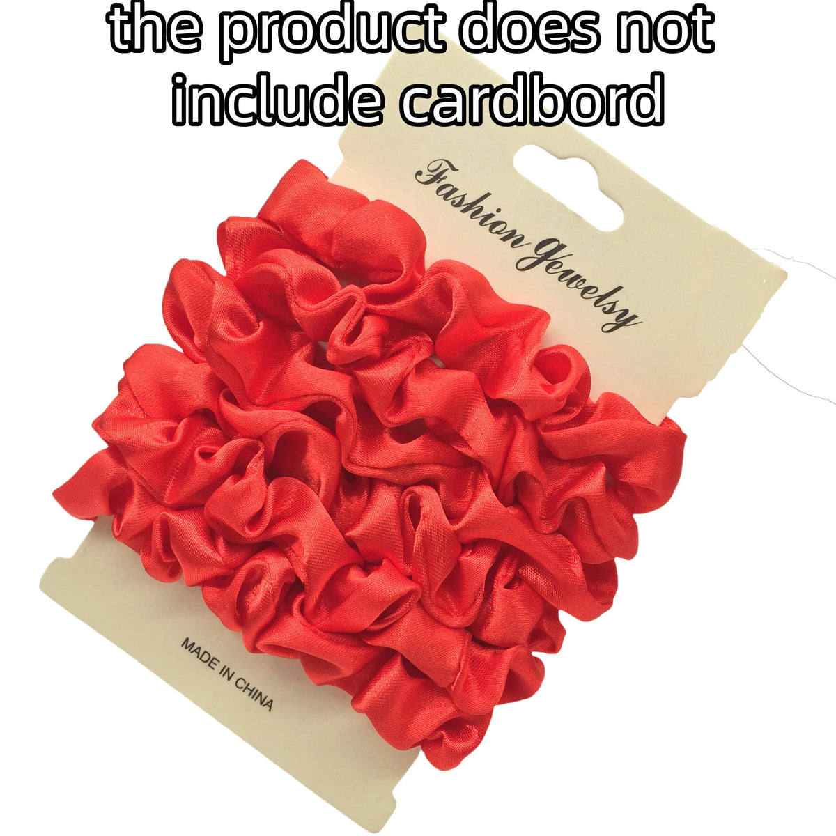 A pile of red satin hair scrunchies displayed on a cardboard tag.