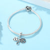 Silver bracelet with a heart charm and a family tree charm on a light blue background